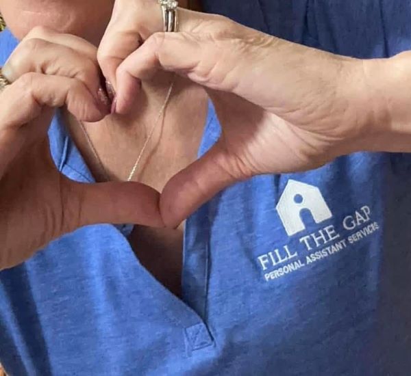 staff member from Fill the Gap Personal Assistant Services makes a heart shape with their hands to symbolize care and compassion